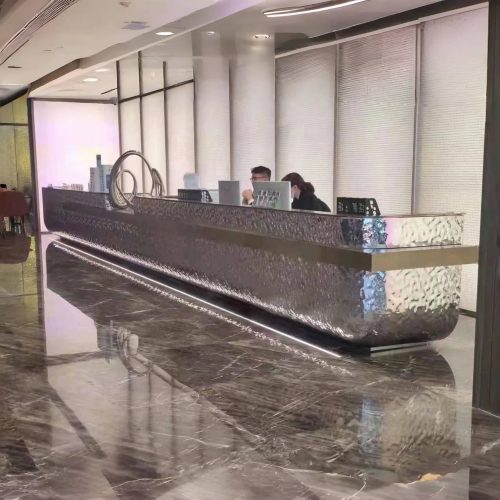 Custom large-scale stainless steel reception desk with premium brushed finish, spacious countertop, and clean modern lines, installed in a luxury corporate lobby.
