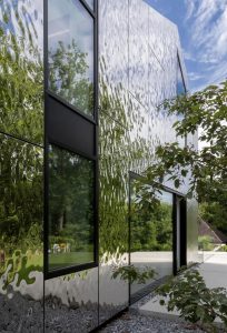 Modern building facade clad with water ripple stainless steel exterior panels, dynamic wave texture, metallic reflections, and contemporary architectural design.